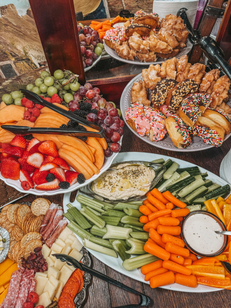 A large brunch grazing table featuring fresh waffles, donuts, fruit, and charcuterie for a women's crafting workshop.