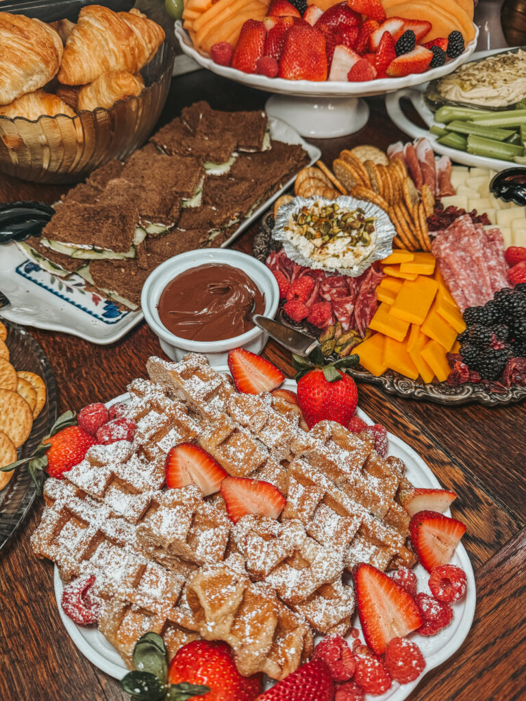 A large brunch grazing table featuring fresh waffles, donuts, fruit, and charcuterie for a women's crafting workshop.
