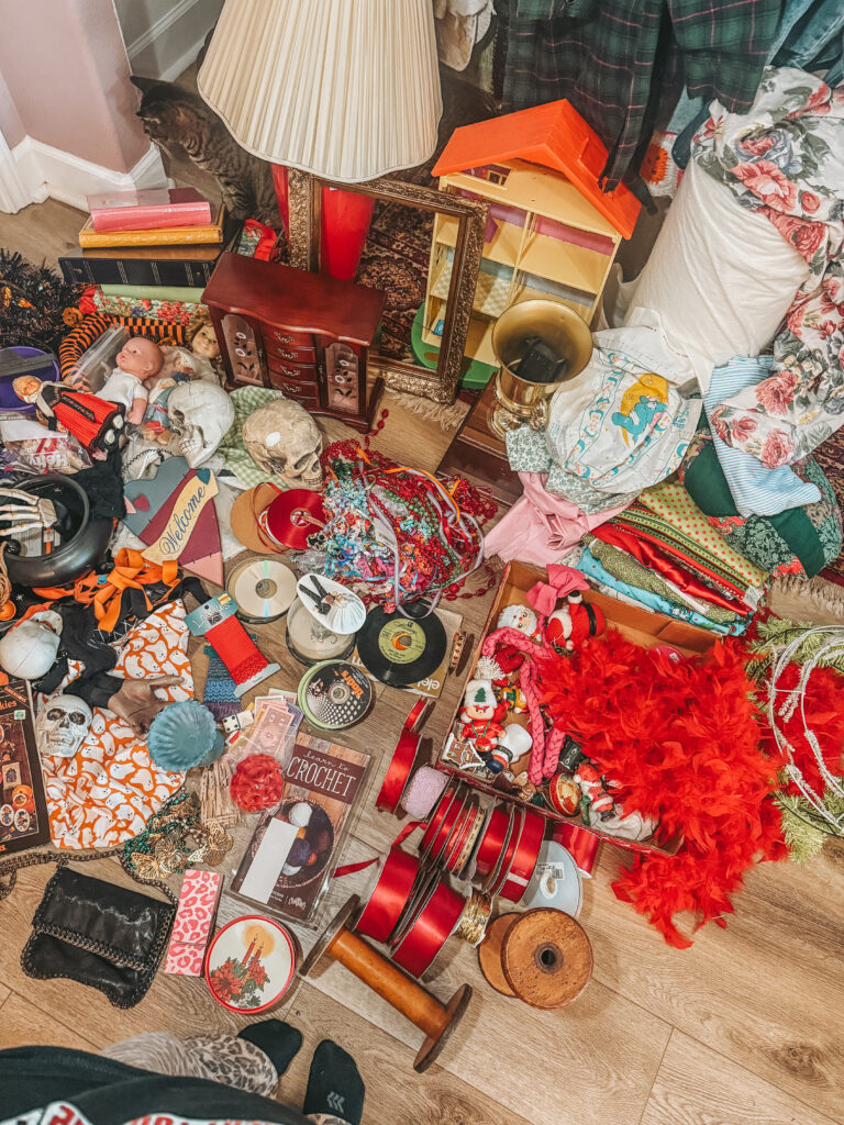 Close-up of mixed vintage items from Goodwill bins, featuring spools of ribbon, old records, fabric scraps, and unique crafting materials in bright colors.