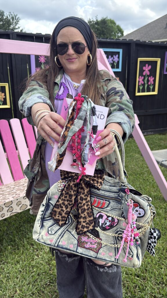 Woman in a camo jacket holding books and a highly decorated DIY Y2K denim charm purse.