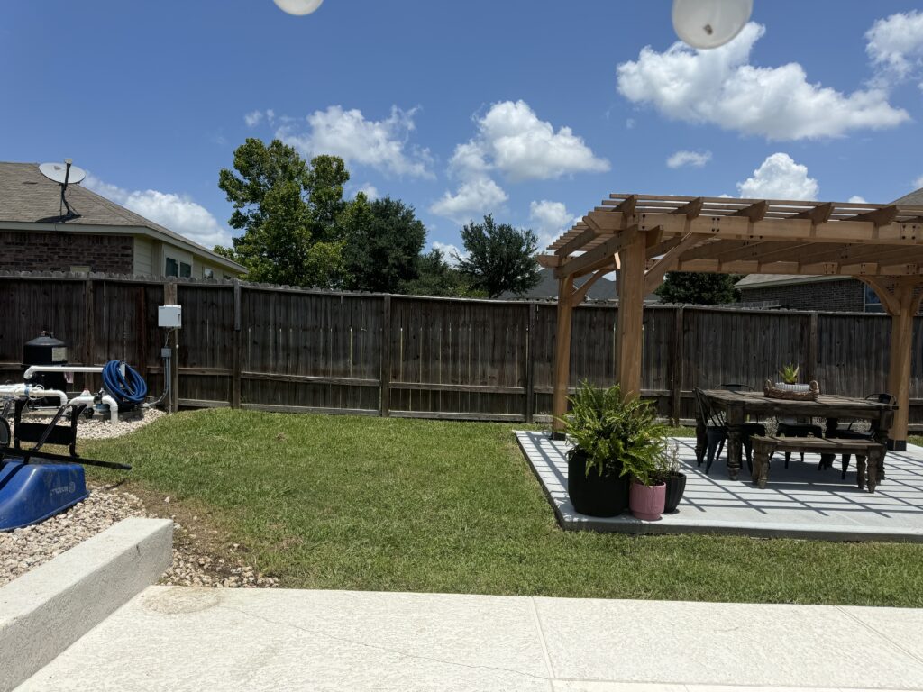 plain grass yard with a basic wooden pergola and a weathered swing set.